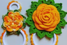 Porta-pano de prato em crochê com flores coloridas em tons de laranja e verde, ideal para decorar e organizar a cozinha