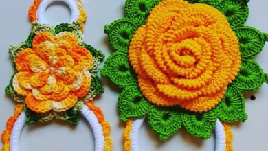 Porta-pano de prato em crochê com flores coloridas em tons de laranja e verde, ideal para decorar e organizar a cozinha