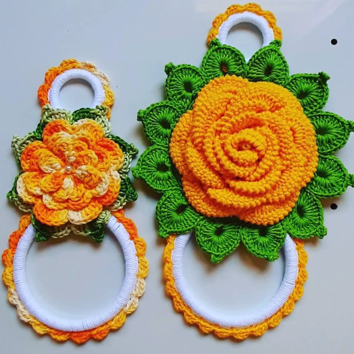 Porta-pano de prato em crochê com flores coloridas em tons de laranja e verde, ideal para decorar e organizar a cozinha