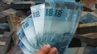 Pessoa segura notas de 100 reais, representando saque do Caixa Tem.