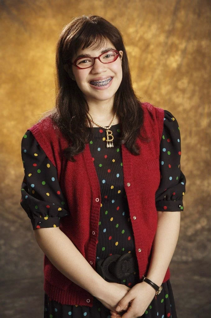 Cena de Ugly Betty, mostrando a personagem Betty Suarez com óculos e aparelho