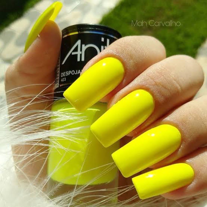 Unhas amarelo neon: a cor que está deixando espaço para tons mais suaves "Unhas com esmalte amarelo neon, destacando a cor vibrante em contraste com o fundo.