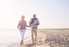 Casal de idosos caminhando na praia ao amanhecer