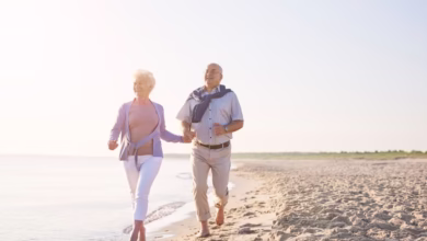 Casal de idosos caminhando na praia ao amanhecer