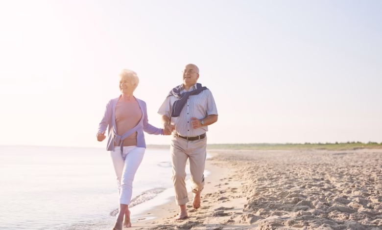 Casal de idosos caminhando na praia ao amanhecer