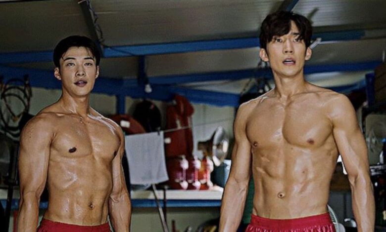 Os atores Woo Do-hwan e Lee Sang-yi, sem camisa, mostrando o físico musculoso em uma cena de treinamento de boxe do dorama ‘Cães de Caça’.