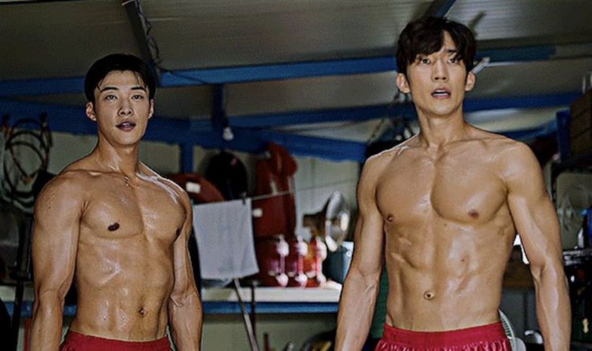 Os atores Woo Do-hwan e Lee Sang-yi, sem camisa, mostrando o físico musculoso em uma cena de treinamento de boxe do dorama ‘Cães de Caça’.