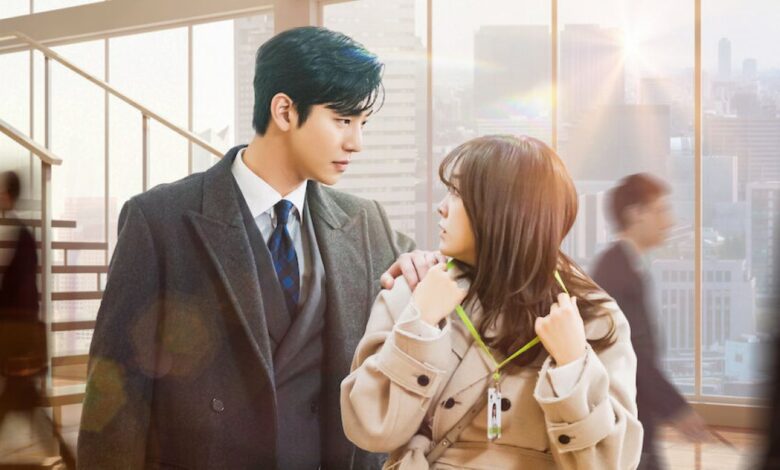 Cena do dorama Pretendente Surpresa com o protagonista masculino gentilmente tocando o ombro da protagonista feminina em um escritório.