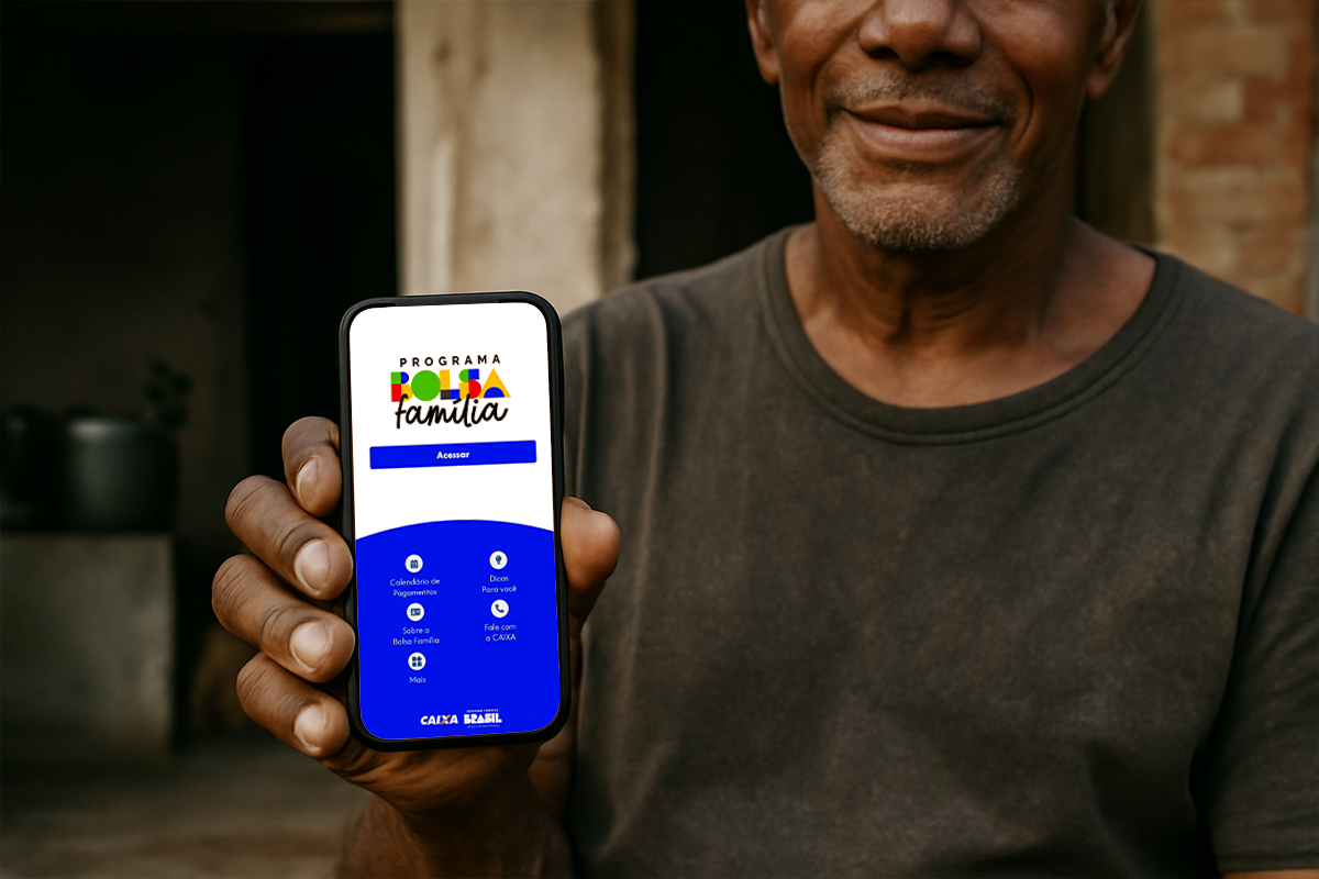 Um celular com o aplicativo do Programa Bolsa Família aberto, sendo segurado por uma pessoa de pele morena.