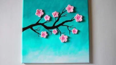 Crochê de parede com ramo de flor de cerejeira em fundo azul, peça decorativa artesanal com flores crocheted.
