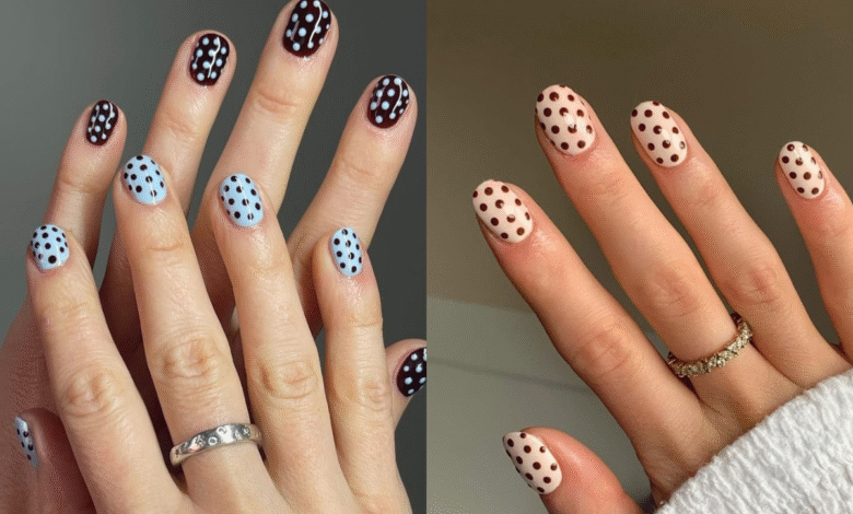 Mãos com unhas decoradas com estampa de bolinhas (poá) em diferentes cores, uma em azul claro com bolinhas pretas e a outra em tom de nude com bolinhas marrons.
