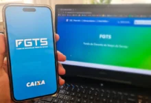Uma mão segura um maço de notas de R$ 100 ao lado de um smartphone que exibe o logo do FGTS. A imagem simboliza a regularização financeira de débitos relacionados ao Fundo de Garantia.