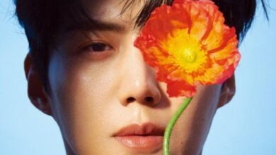 O ator coreano Kim Seon-ho em uma foto de capa de revista, com duas flores vermelhas cobrindo parte de seu rosto.