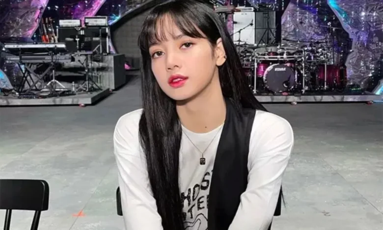 Lisa do BLACKPINK em ambiente de palco, com cabelo longo e liso, vestindo uma camiseta branca com estampa