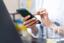 Mãos usando um celular para navegar nas novas opções de privacidade do WhatsApp.