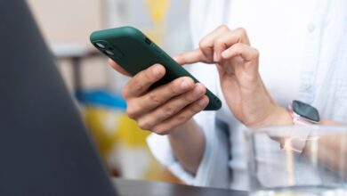 Mãos usando um celular para navegar nas novas opções de privacidade do WhatsApp.