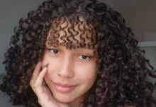 Mulher com cabelo cacheado e franja, estilo moderno e volumoso, mostrando como modelar cabelos cacheados com franja