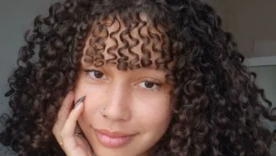 Mulher com cabelo cacheado e franja, estilo moderno e volumoso, mostrando como modelar cabelos cacheados com franja