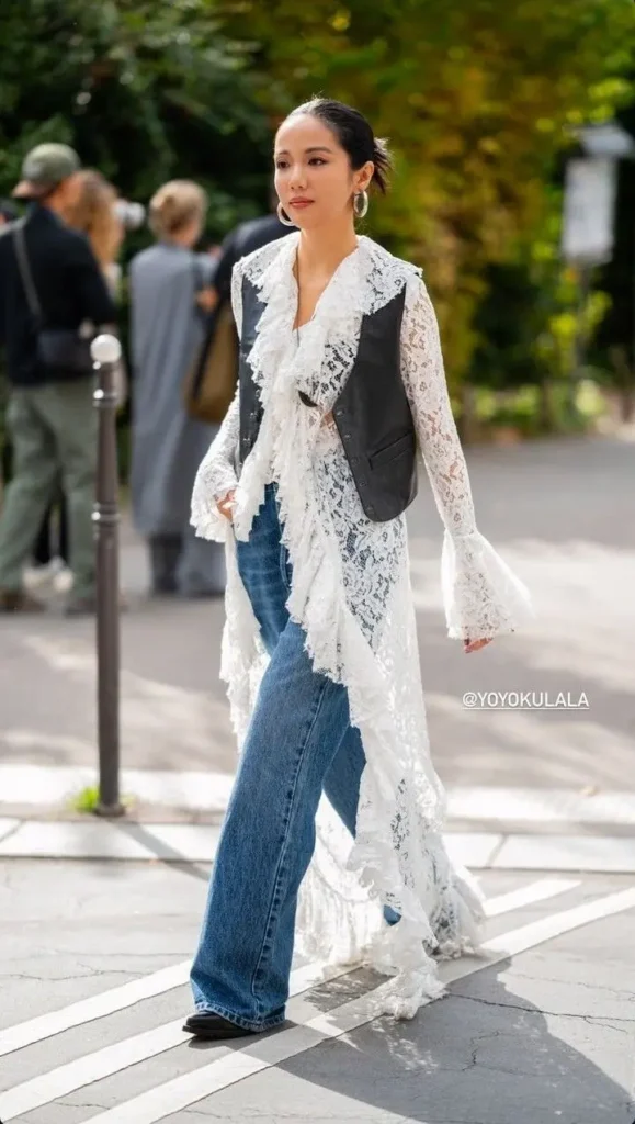 Mulher com estilo boho moderno usando uma camisa transparente de renda e jeans.