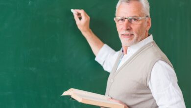 Professor sênior escrevendo em quadro-negro com giz, representando as mudanças nas regras de aposentadoria para educadores.