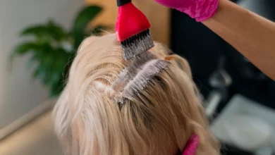 Aplicação de coloração fantasia em cabelo de mulher com luvas rosas, destacando tendências para mulheres acima dos 40.
