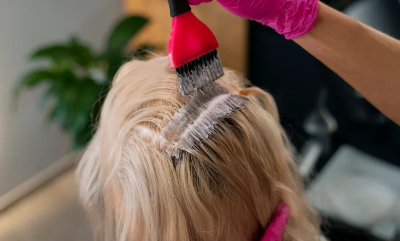 Aplicação de coloração fantasia em cabelo de mulher com luvas rosas, destacando tendências para mulheres acima dos 40.