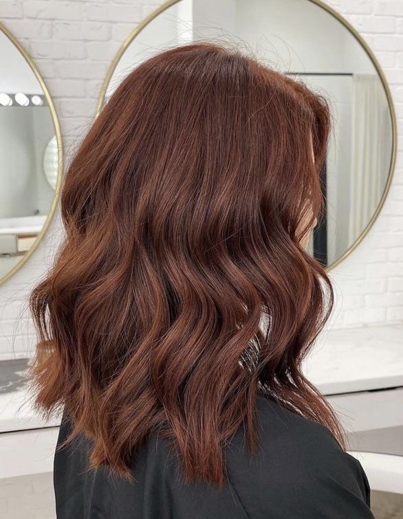 Mulher de costas com cabelo na tonalidade castanho apimentado, mostrando o tom com reflexos avermelhados e canelados.