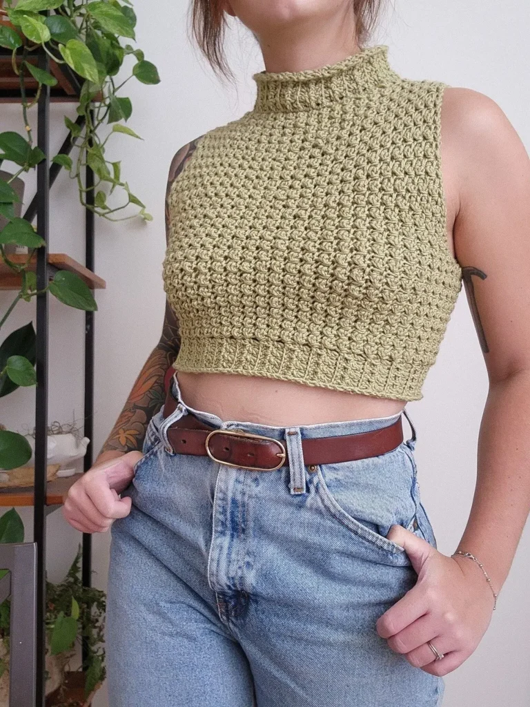 Mulher usando um modelo de crochê com gola alta e sem mangas, destacando o estilo artesanal e sofisticado.