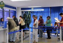 Uma fila de pessoas, incluindo idosos, aguarda atendimento em um balcão da Previdência Social no Brasil.