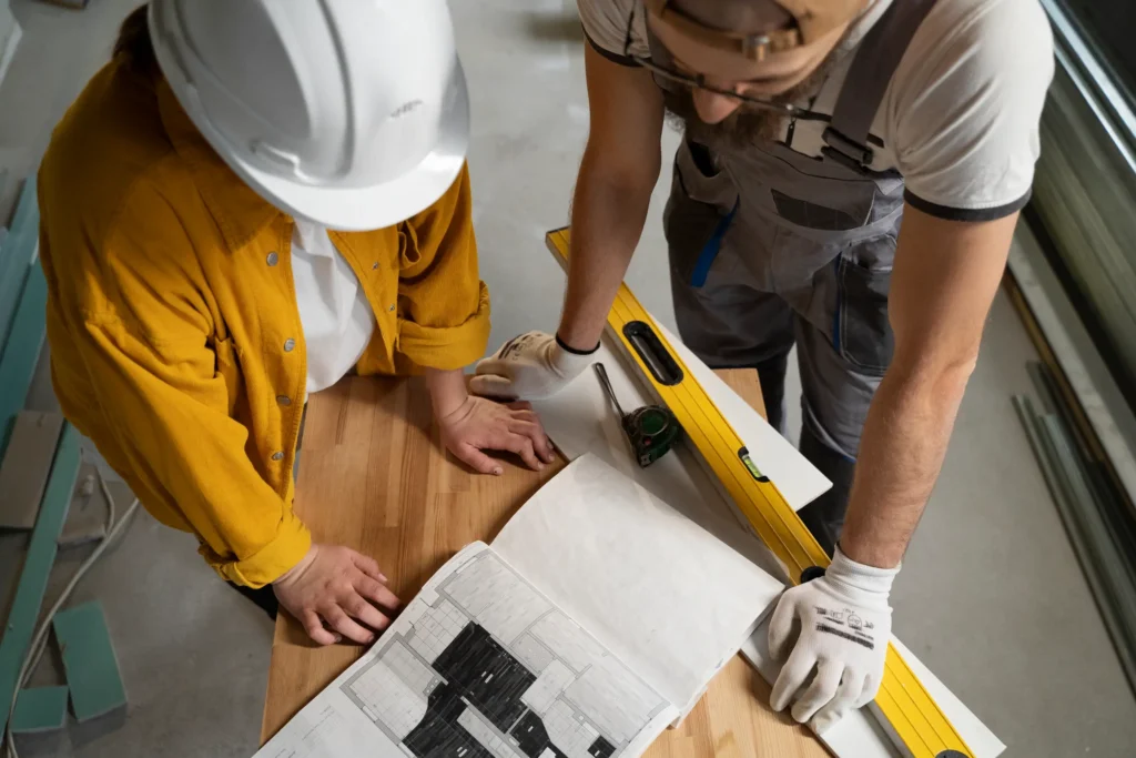 Profissionais da construção civil analisando plantas de reforma de casa.