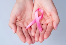 Fita rosa em mãos, representando o Outubro Rosa e a campanha de prevenção ao câncer de mama.
