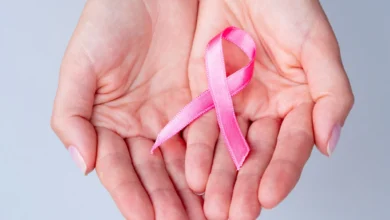Fita rosa em mãos, representando o Outubro Rosa e a campanha de prevenção ao câncer de mama.