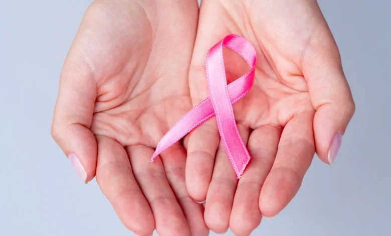 Fita rosa em mãos, representando o Outubro Rosa e a campanha de prevenção ao câncer de mama.