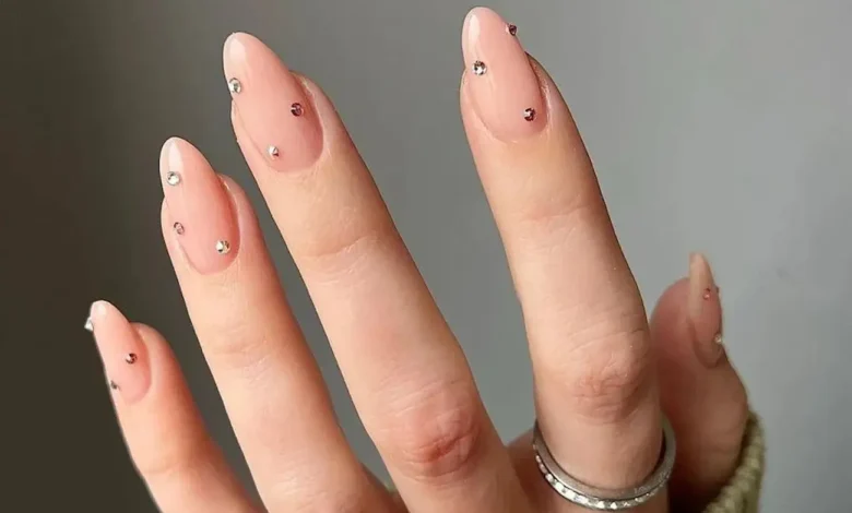 Unhas com pedrarias minimalistas em tons neutros, com design simples e elegante, ideal para quem busca sofisticação sem exageros.