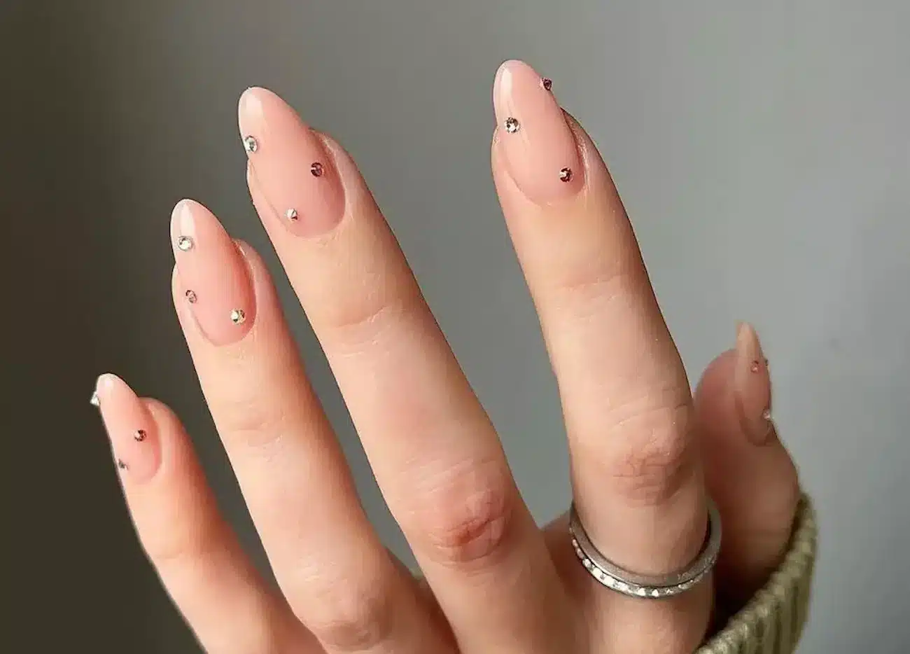 Unhas com pedrarias minimalistas em tons neutros, com design simples e elegante, ideal para quem busca sofisticação sem exageros.