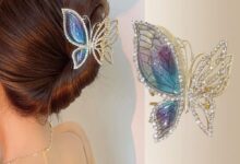 Mulher com coque e presilha de cabelo de borboleta azul e dourada, cravejada de pedras.