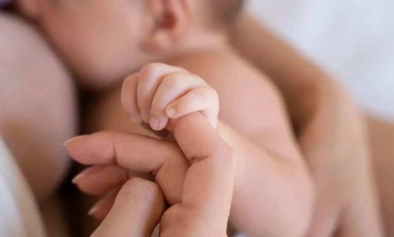 Mãe segurando a mão de seu bebê recém-nascido em um momento de carinho e cuidado no período pós-natal.