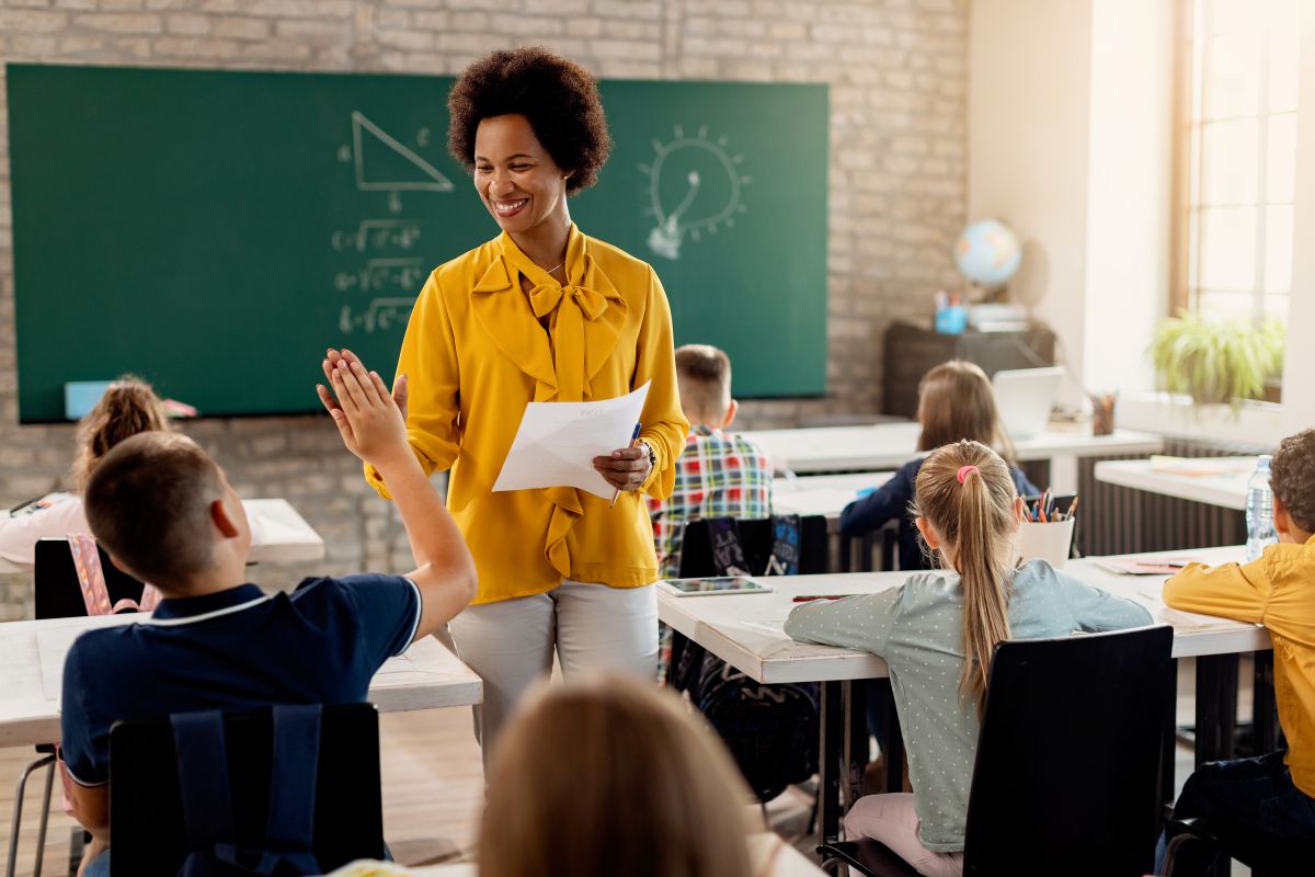 Professora sorrindo e interagindo com os alunos em sala de aula, representando a nova geração de educadores sob as regras de aposentadoria pós-reforma.