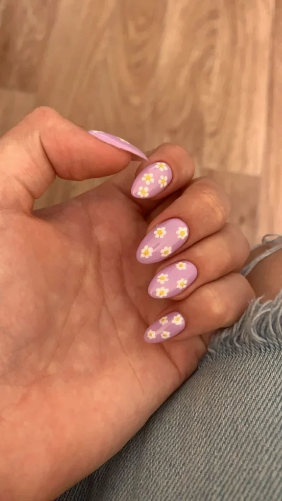 Unhas decoradas com esmalte rosa e detalhes florais.