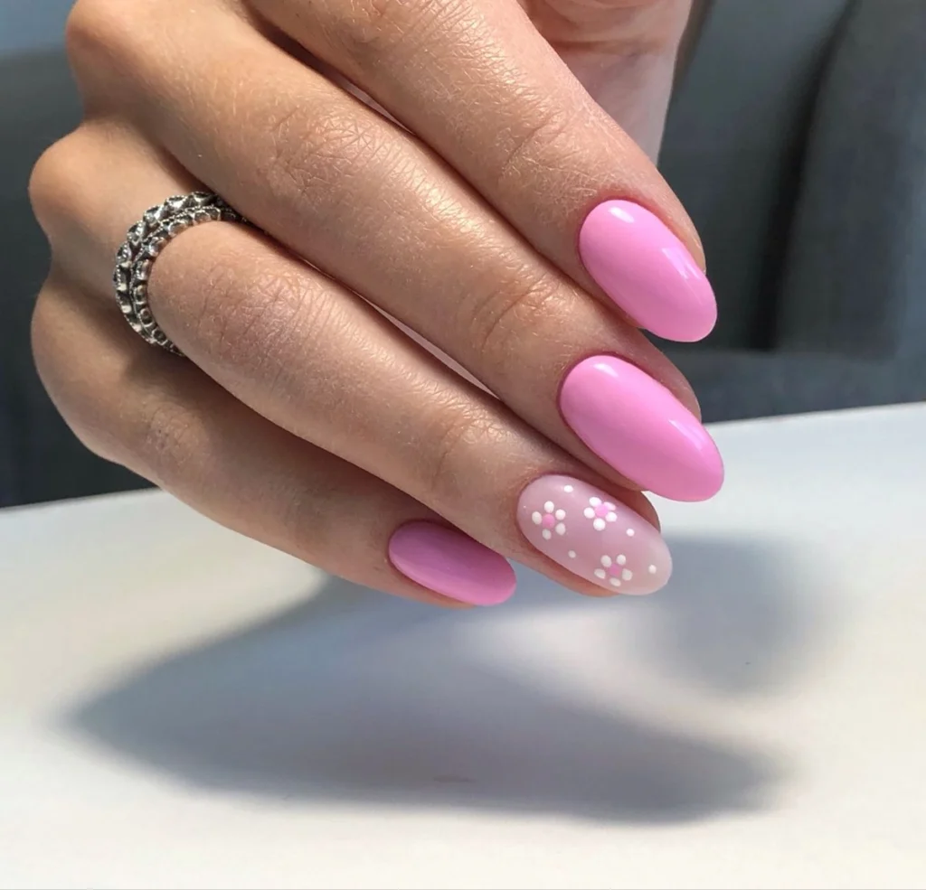Unhas decoradas com esmalte rosa e detalhes florais delicados em fundo branco