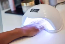 Unha sendo tratada com esmalte em gel usando lâmpada UV em um salão de beleza.