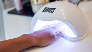 Unha sendo tratada com esmalte em gel usando lâmpada UV em um salão de beleza.