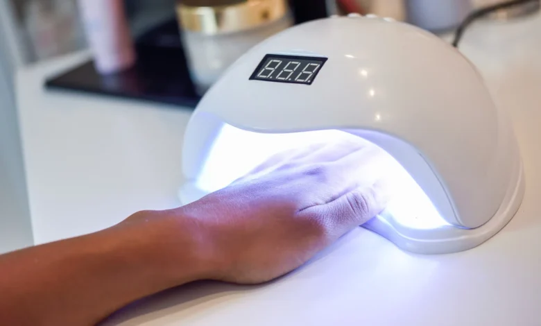 Unha sendo tratada com esmalte em gel usando lâmpada UV em um salão de beleza.