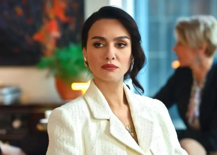 Mulher elegante com expressão séria em uma reunião, representando personagem de Asas da Ambição.