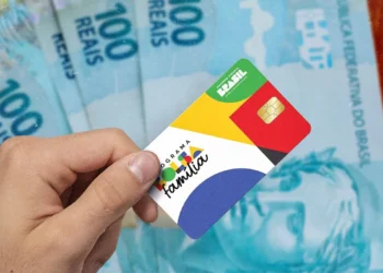 Cartão do Bolsa Família com cédulas de 100 reais ao fundo, tema Governo finaliza pagamentos.