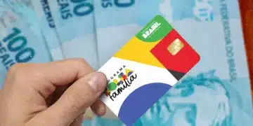 Cartão do Bolsa Família com cédulas de 100 reais ao fundo, tema Governo finaliza pagamentos.