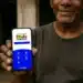 Homem mostrando celular com tela do Programa Bolsa Família Brasil com opções de acesso e informações