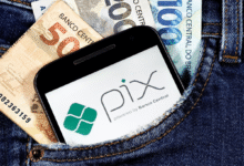 Celular com logo do PIX no bolso de calça junto a notas de real.