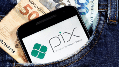 Celular com logo do PIX no bolso de calça junto a notas de real.