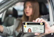 Pessoa mostrando sua CNH digital no celular enquanto está dentro de um carro, ilustrando a digitalização do processo de habilitação no Brasil.
